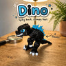 Dino 3D printed articulated flexi toy by Cosmic 3D Creations, on a wooden desk with a fern