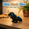 Mini Black Dino 3D printed articulated flexi toy by Cosmic 3D Creations, on a wooden desk with a fern