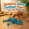 Skeleton Saber Toothed Tigers 3D printed articulated flexi toy by Cosmic 3D Creations, on a wooden desk with a fern