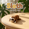 Sloth 3D printed articulated flexi toy by Cosmic 3D Creations, on a sunlit table with tropical leaves