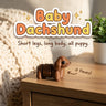 Baby Dachshund 3D printed articulated flexi toy, on a cozy side table with a knit blanket