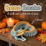 Bone Snake 3D printed articulated flexi toy by Cosmic 3D Creations, on a cozy autumn shelf with pumpkins