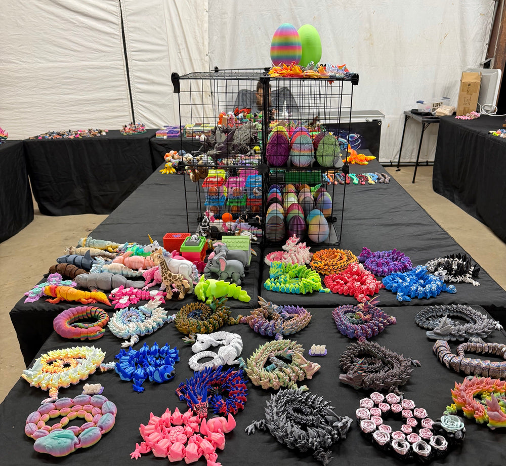 Our Canton Trade Days booth table covered in 3D printed flexi dragons, dragon eggs and animals