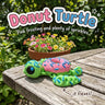 Donut Turtle 3D printed articulated flexi toy by Cosmic 3D Creations, on a sunny garden table with flowers