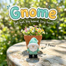 Gnome 3D printed articulated flexi toy by Cosmic 3D Creations, on a sunny garden table with flowers
