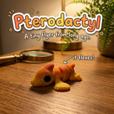 Pterodactyl 3D printed articulated flexi toy by Cosmic 3D Creations, on a wooden desk with a fern