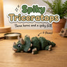 Spiky Triceratops 3D printed articulated flexi toy by Cosmic 3D Creations, on a wooden desk with a fern